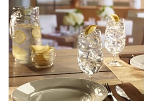 A close-up of a table setting featuring clear glasses of lemon water filled with large, hard Hoshizaki crescent ice, set in a bright, modern restaurant environment