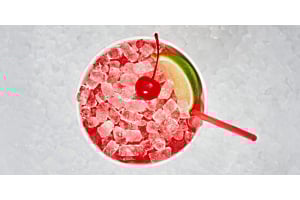 Overhead view of a red beverage filled with Hoshizaki Cubelet ice, garnished with a cherry and a lime slice