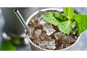 A close-up of a refreshing cocktail in a silver cup, garnished with mint leaves and filled with crushed ice produced by a Hoshizaki flaked ice machine