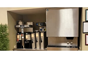 A self-service beverage station featuring a stainless steel Hoshizaki ice and water dispenser positioned next to multiple coffee brewers and insulated carafes
