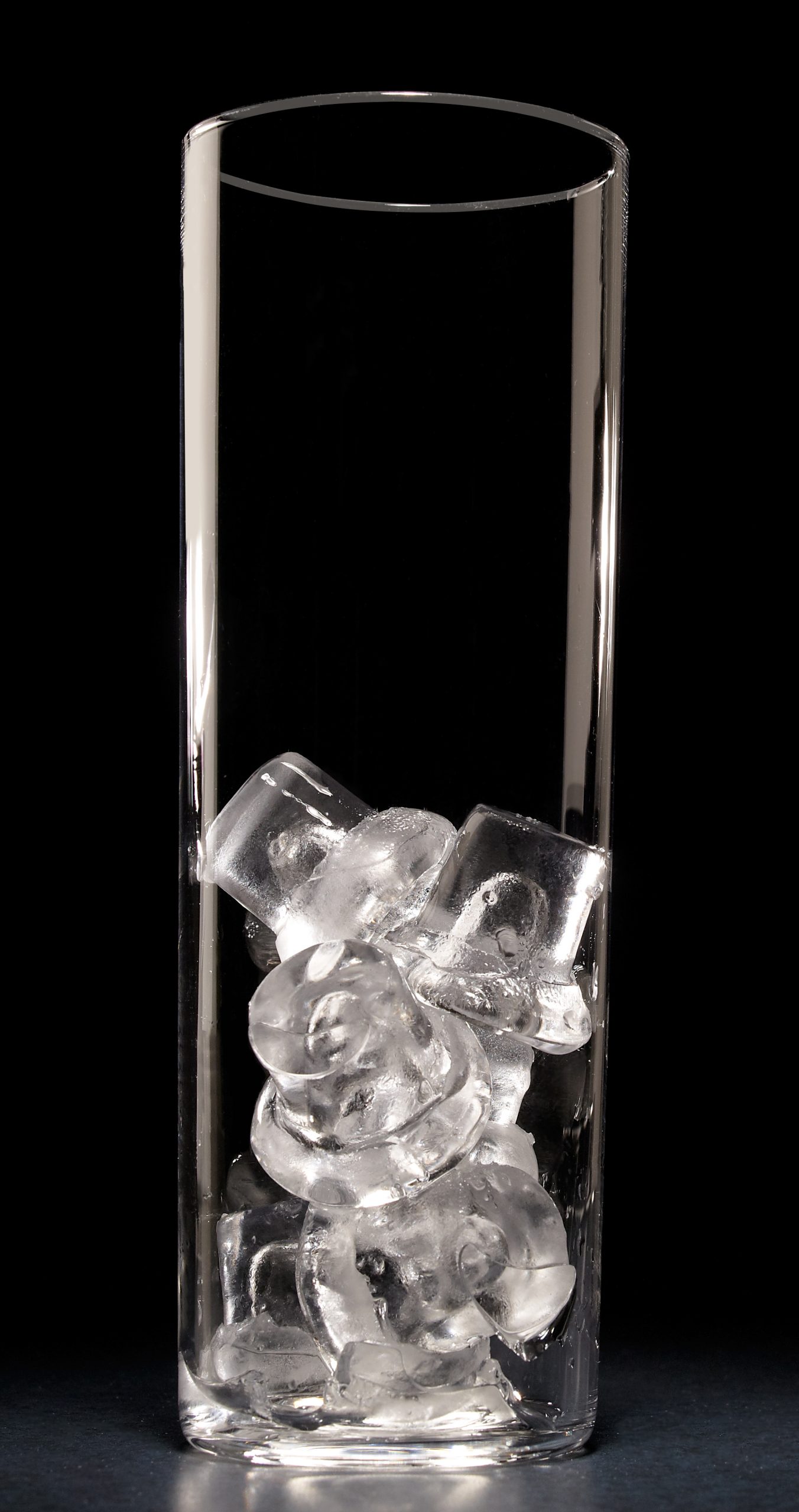 Close-up of a tall, clear glass containing Hoshizaki Crescent Ice cubes against a black background
