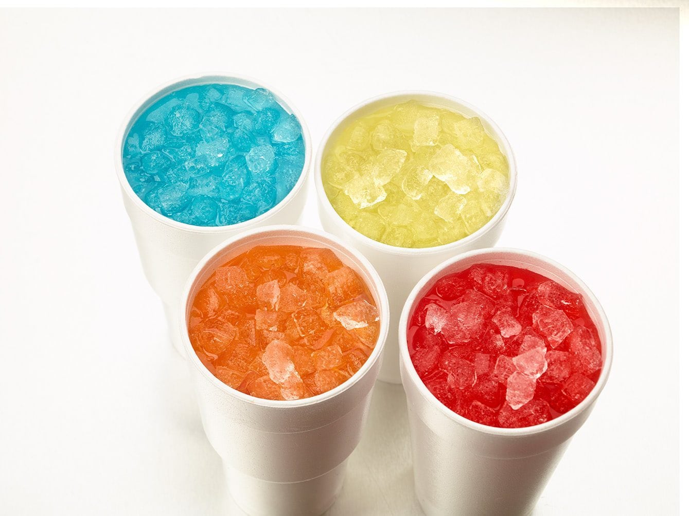 Four Styrofoam cups filled with brightly colored sodas and Hoshizaki Cubelet ice, viewed from above