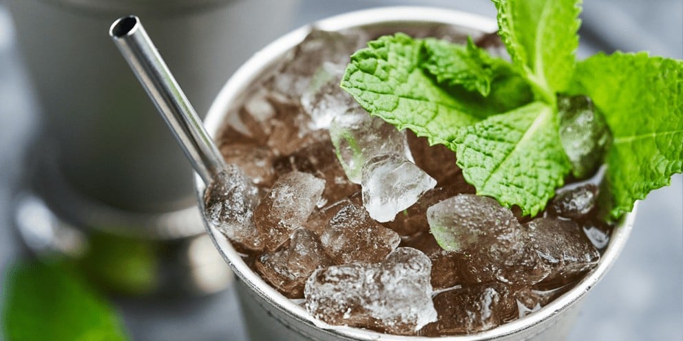 A close-up of a refreshing cocktail in a silver cup, garnished with mint leaves and filled with crushed ice produced by a Hoshizaki flaked ice machine