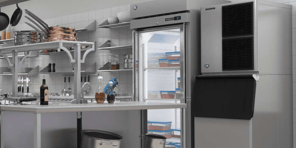 A commercial kitchen scene featuring a Hoshizaki Modular Crescent Cuber ice machine stacked on a matching bin next to a glass-door reach-in refrigerator